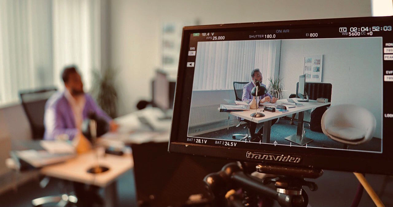 Office scene shown on a production monitor during filming